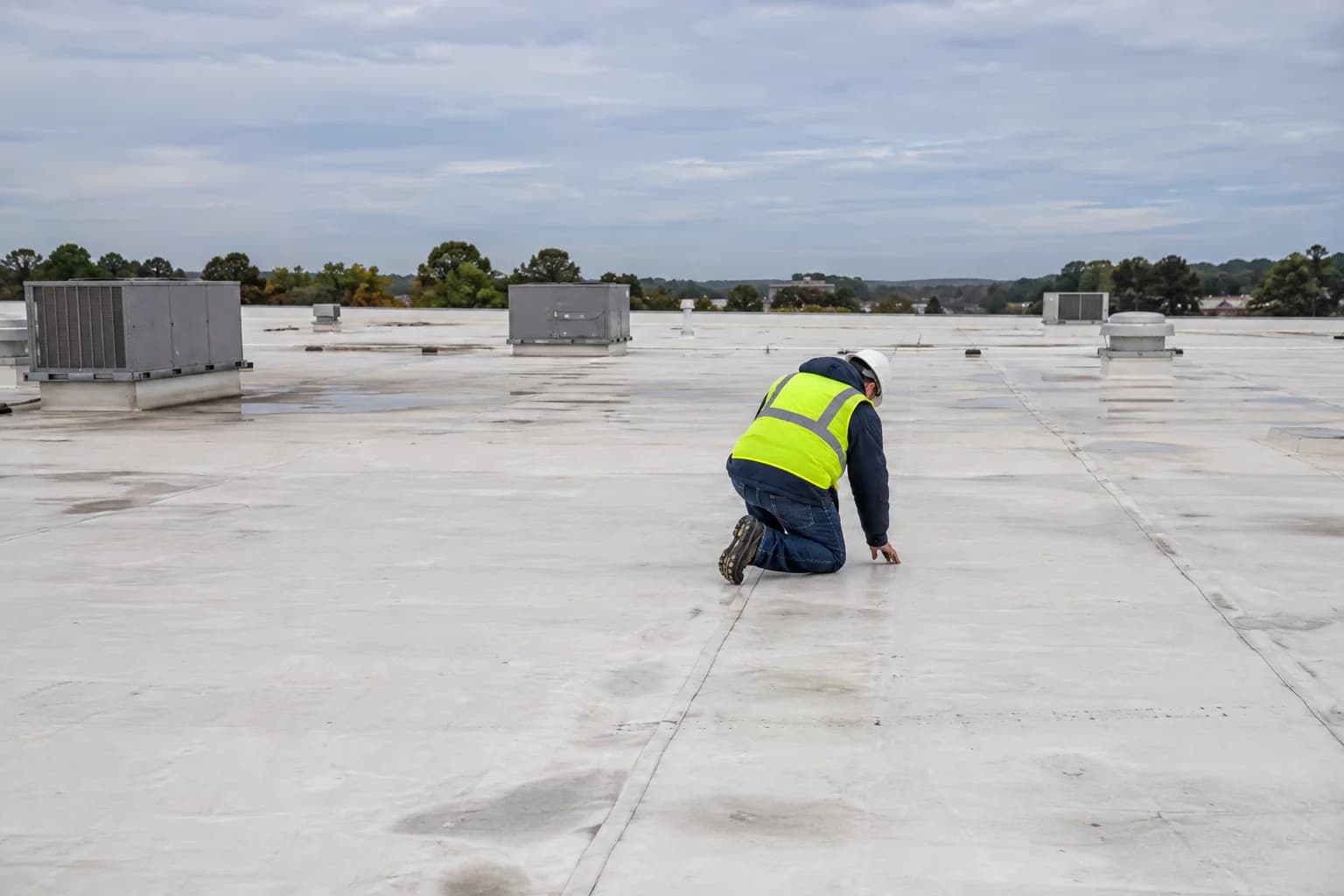 A consultant examining a seam on a weathered commercial roof
