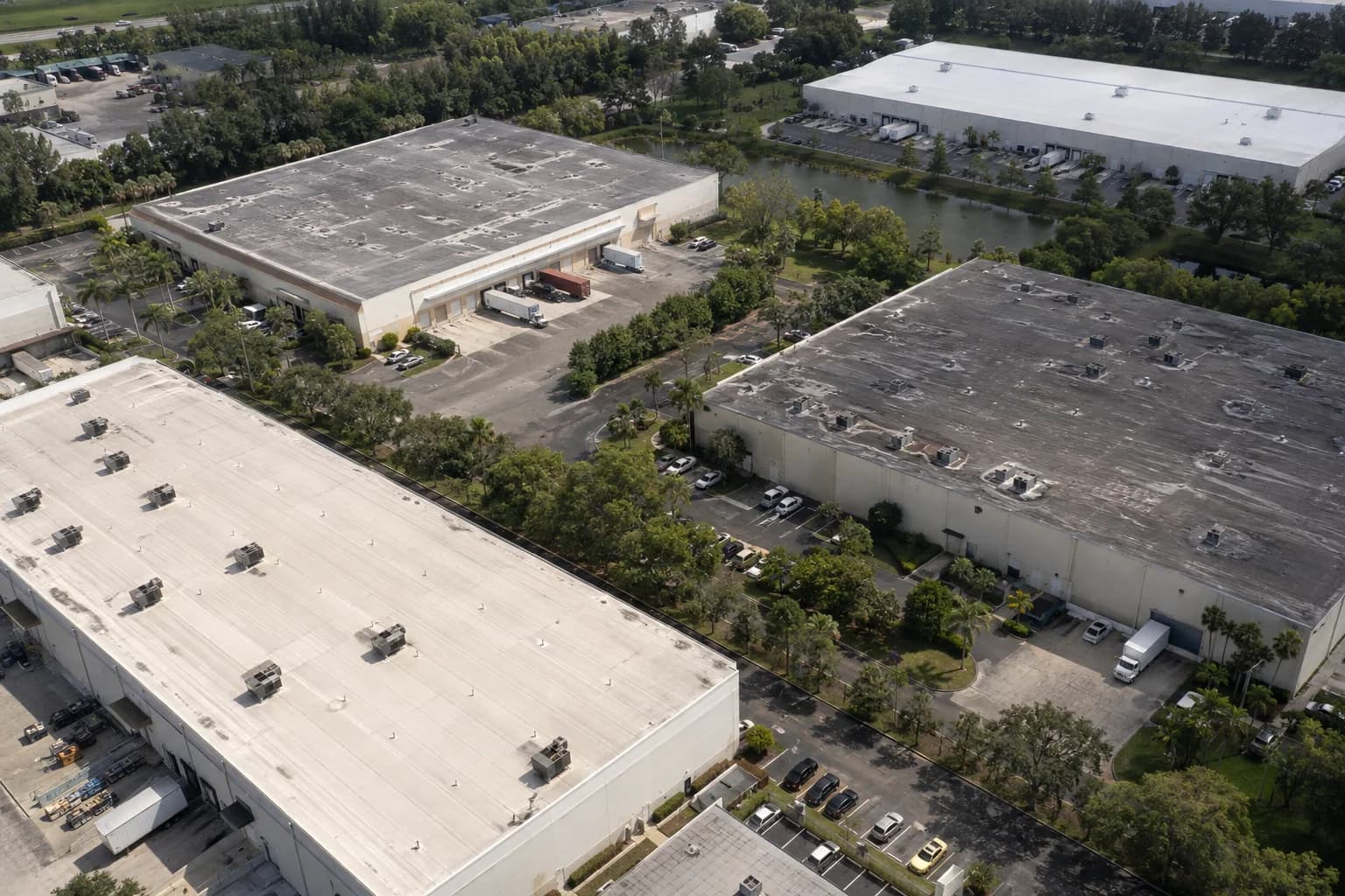 Aerial view of warehouse roofs, loading bays, and tree-lined access roads