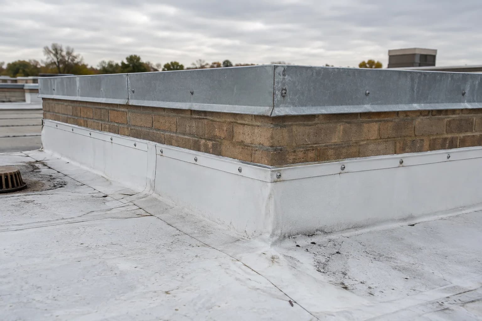 Membrane flashing and metal coping at a commercial roof parapet
